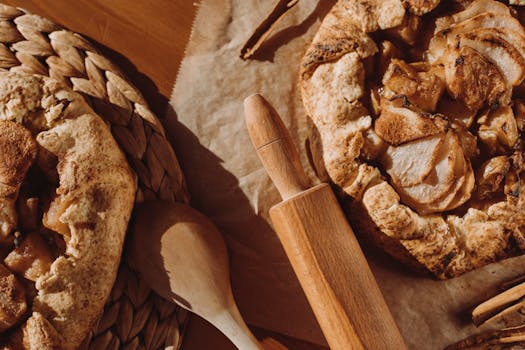 Tartes aux pommes maison sur une table en bois avec un rouleau à pâtisserie et une cuillère en bois.