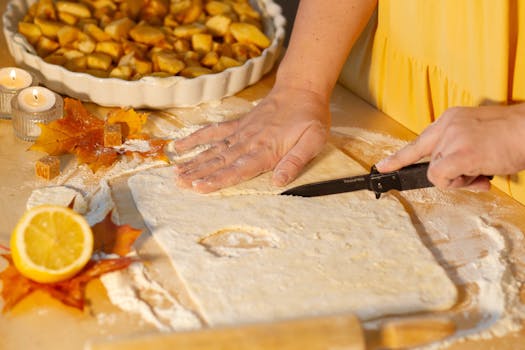 Préparation de la pâte à tarte pour une tarte aux pommes, avec des pommes coupées et des décorations automnales.