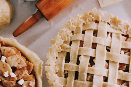Deux tartes aux pommes maison sur une surface de travail, l'une avec une croûte tressée et l'autre garnie de pommes.