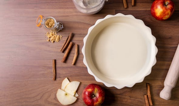 Ingrédients pour une tarte aux pommes : pommes rouges, cannelle, sucre brun, pâte à tarte et rouleau à pâtisserie sur une tab